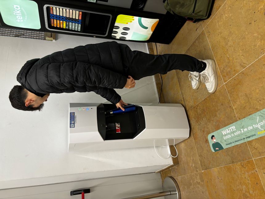 Estudiante llenando una botella en la fuente y al lado las máquinas de vending